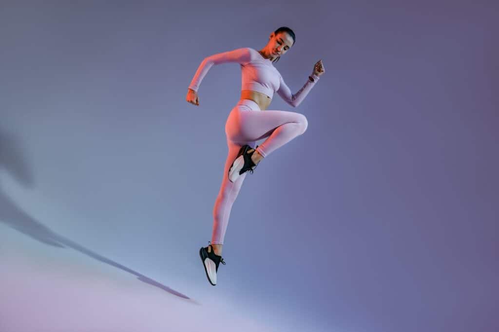 Attractive sporty woman in sportswear jumping on studio background. Sport and healthy lifestyle